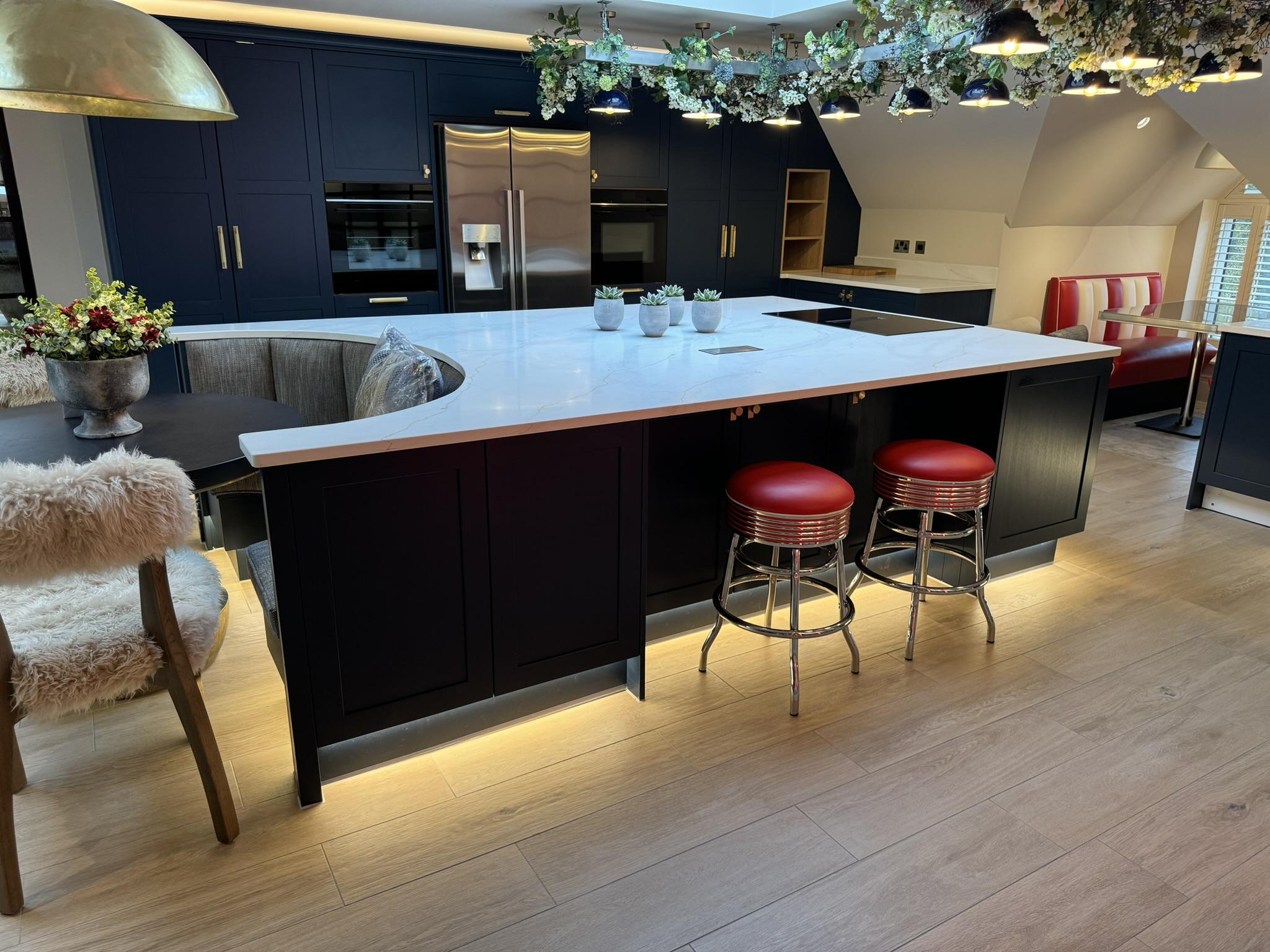 Stylish kitchen with white counters and red bar stools under pendant lights
